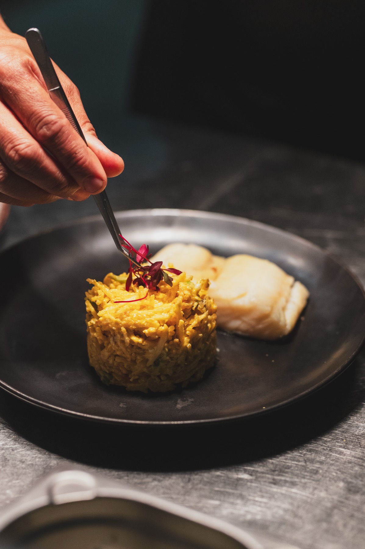 A plated dish being finished by hand in the Villa Sabóia kitchen