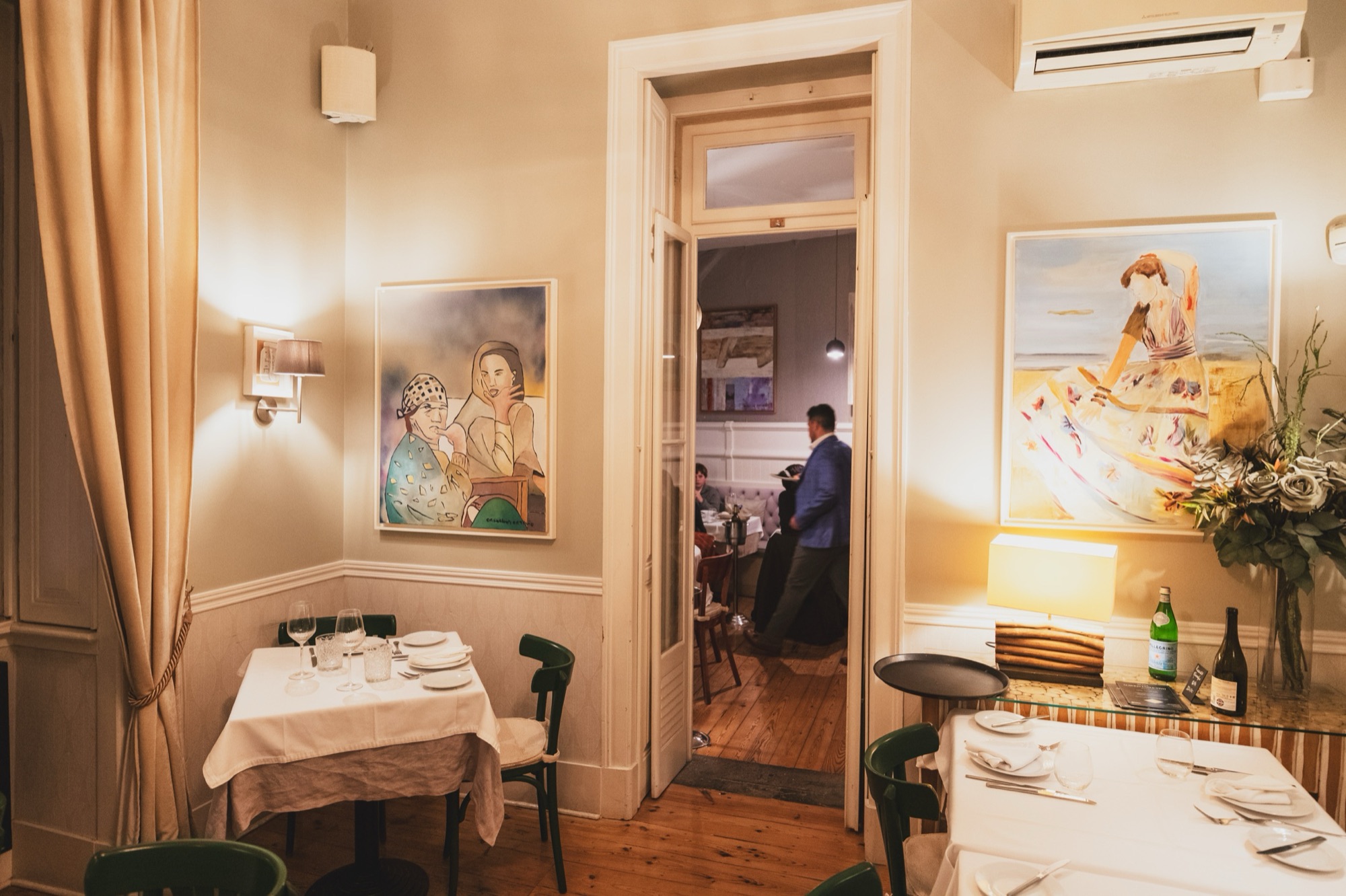 A waiter in a blue jacket passing through a doorway between two dining rooms at Villa Sabóia