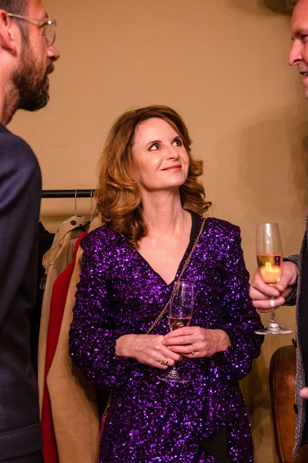 Beile Grünbaum in conversation with two guests, glasses in hand